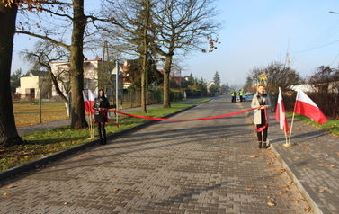 jezdnia z kostki betonowej, flagi oraz dwie dziewczyny z czerwoną wstęgą